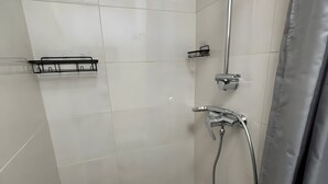 Ducha con cabezal de ducha de mano, grifo empotrado en la pared y cortina de ducha.