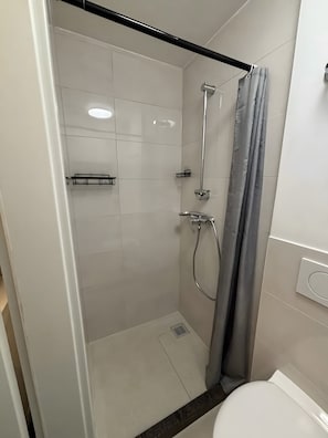 A shower with a glass door, a towel rack, and a showerhead.
