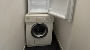 Un lavadero pequeño con lavadora y un refrigerador empotrado.