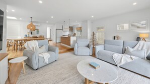 Un salon moderne avec un canapé gris, une petite table ronde et un coin repas doté de meubles en bois.