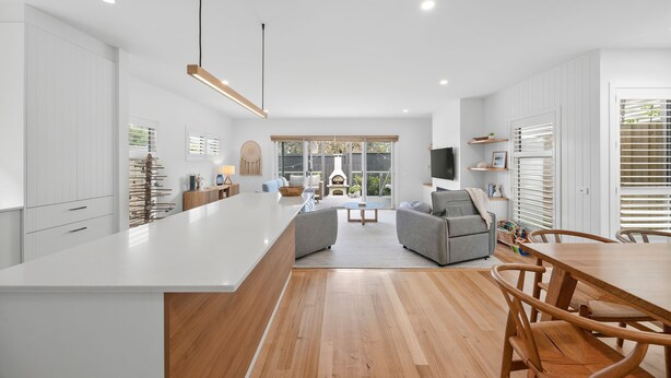 Une cuisine moderne dotée d’un grand îlot central, d’un plancher en bois et d’un coin repas avec une table et des chaises.