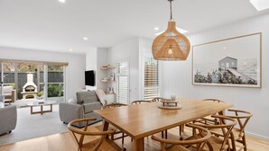 Un espace repas moderne avec une table et des chaises en bois, un luminaire suspendu et un tableau encadré au mur.