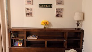 A room with a wooden bookshelf, a lamp, and several framed quotes on the wall.