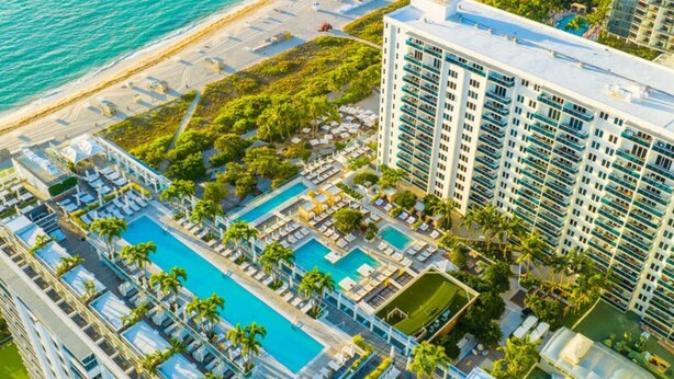 A high-rise hotel with multiple swimming pools, a beach, and lush greenery. - Villa DecoBlu (Miami Beach)