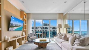 A modern living room with a large TV, comfortable seating, and a view of the cityscape through large windows. - Villa DecoBlu (Miami Beach)