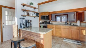Una cocina con armarios de madera, encimera de granito y barra con taburetes.