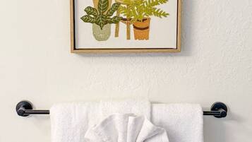 En indrammet illustration af forskellige planter på en væg, med et hvidt håndklæde hængende under.