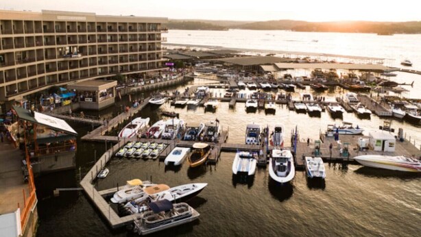 Een jachthaven met veel boten afgemeerd, een groot gebouw met balkons en uitzicht op het water.
