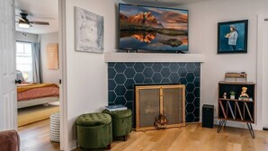 Un salon moderne avec une cheminée, un grand téléviseur et une bibliothèque.