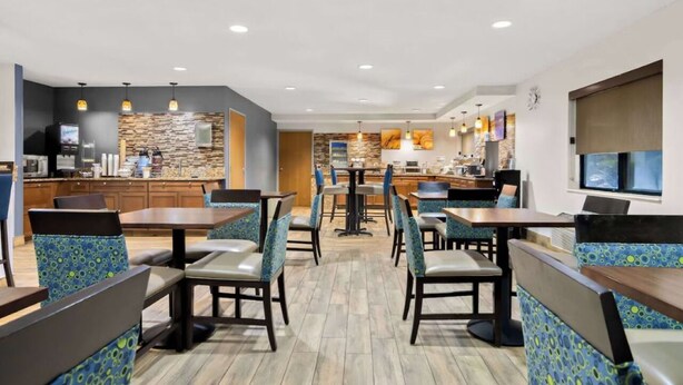 A modern restaurant with booths and tables, a kitchen area, and a stone wall backsplash. - 3 Joliet Hotel Stays with Pool, Gym, and Free Breakfast Near Route 66 Raceway (Joliet)