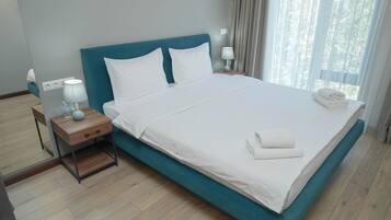 Una cama bien hecha con sábanas blancas y un cabecero color turquesa en una habitación de hotel.