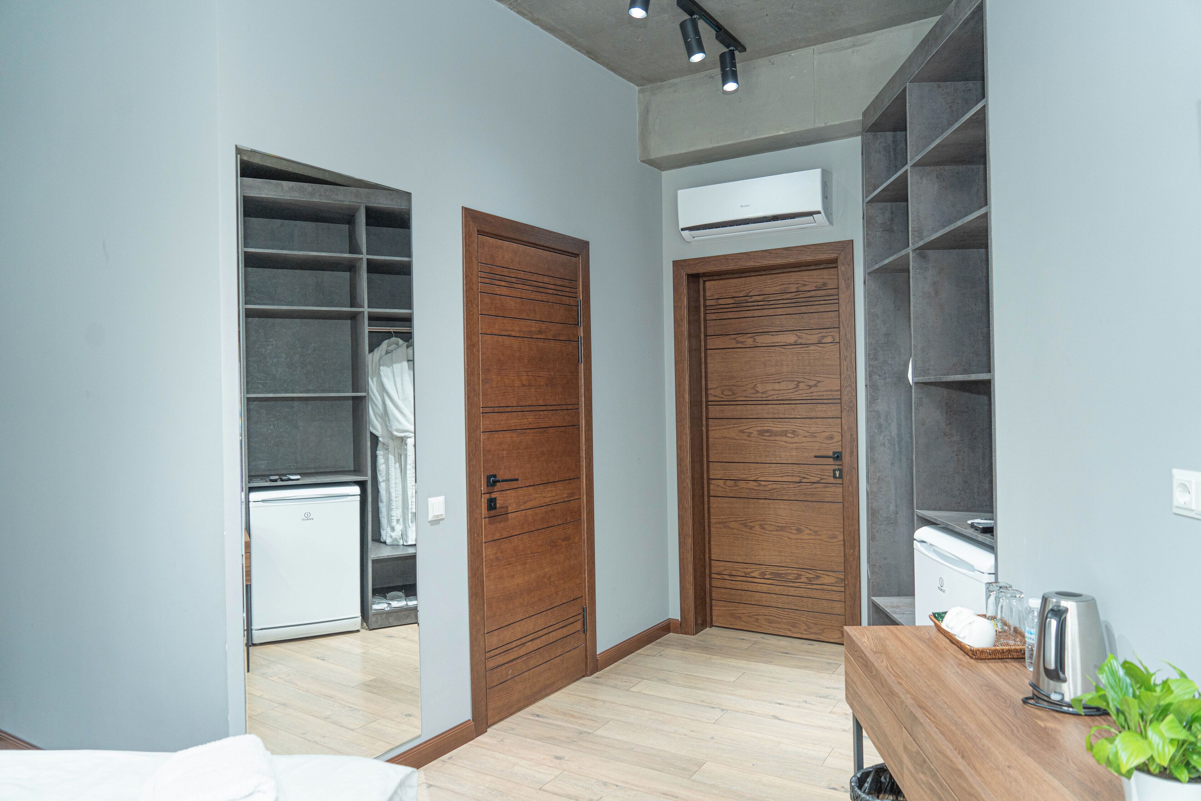 Une chambre compacte comprenant une armoire, un petit coin cuisine et une étagère intégrée.