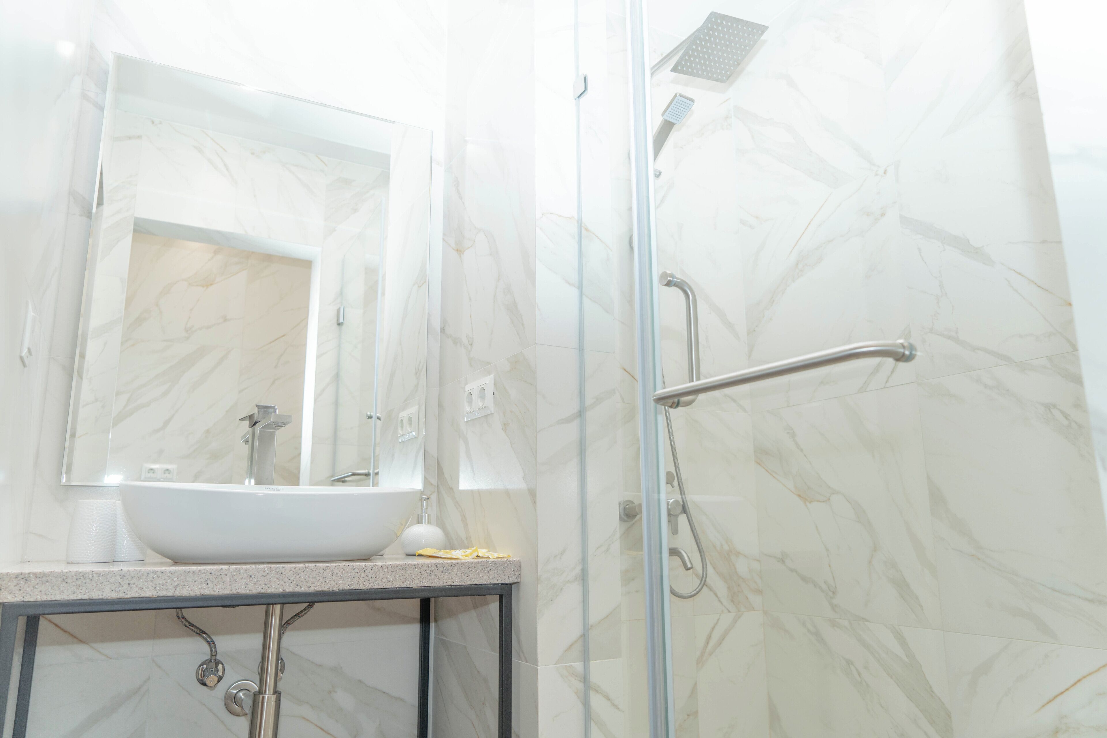 A bathroom with a white sink, mirror, and shower.