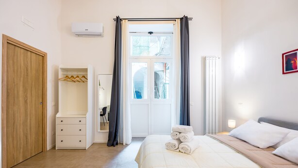 Un dormitorio con cama, armario, closet y ventana con cortinas.