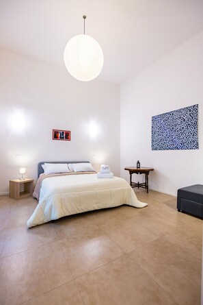 A neatly arranged bedroom with a bed, bedside lamps, a small table, and a wall-mounted artwork. - Art Apartment by Napoliapartments (Naples)