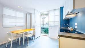 Una cocina moderna con una mesa de madera y sillas blancas, un salpicadero azul y vistas a un balcón.