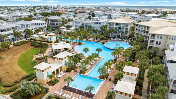 Un resort con varias piscinas, palmeras y vistas al océano.