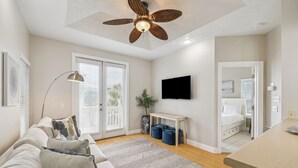 Una sala moderna con ventilador de techo, televisor de pantalla plana, sofá y comedor.