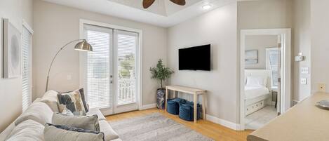 Una sala moderna con ventilador de techo, televisor de pantalla plana, sofá y comedor.