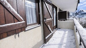 A snow-covered balcony with wooden shutters and a television. - Bright T2 with mountain view and comfort (La Salle-les-Alpes)