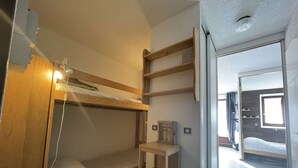 A bunk bed room with a small wooden shelf and a window. - Bright T2 with mountain view and comfort (La Salle-les-Alpes)