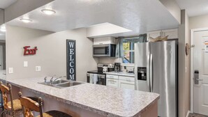 Una cocina moderna con una isla central, electrodomésticos de acero inoxidable y un cartel de 'Welcome'.