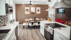 Une cuisine moderne avec un coin repas, un lambris en bois et un téléviseur fixé au mur.