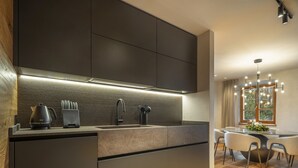 Une cuisine moderne avec des meubles de couleur sombre, un évier en acier inoxydable et une hotte intégrée.