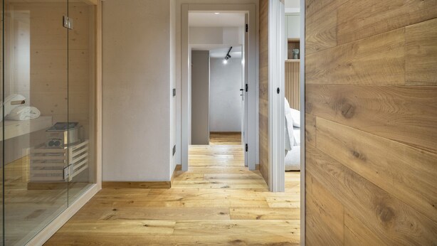Un couloir doté d’un plancher en bois et de portes en verre donnant sur une salle de bain.