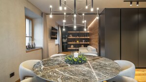 Un espace repas moderne avec une table ronde en marbre, des chaises rembourrées, une bibliothèque intégrée et un luminaire suspendu contemporain.