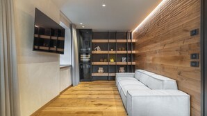 Un intérieur moderne avec un plancher en bois, un canapé blanc, une bibliothèque intégrée et un téléviseur fixé au mur.