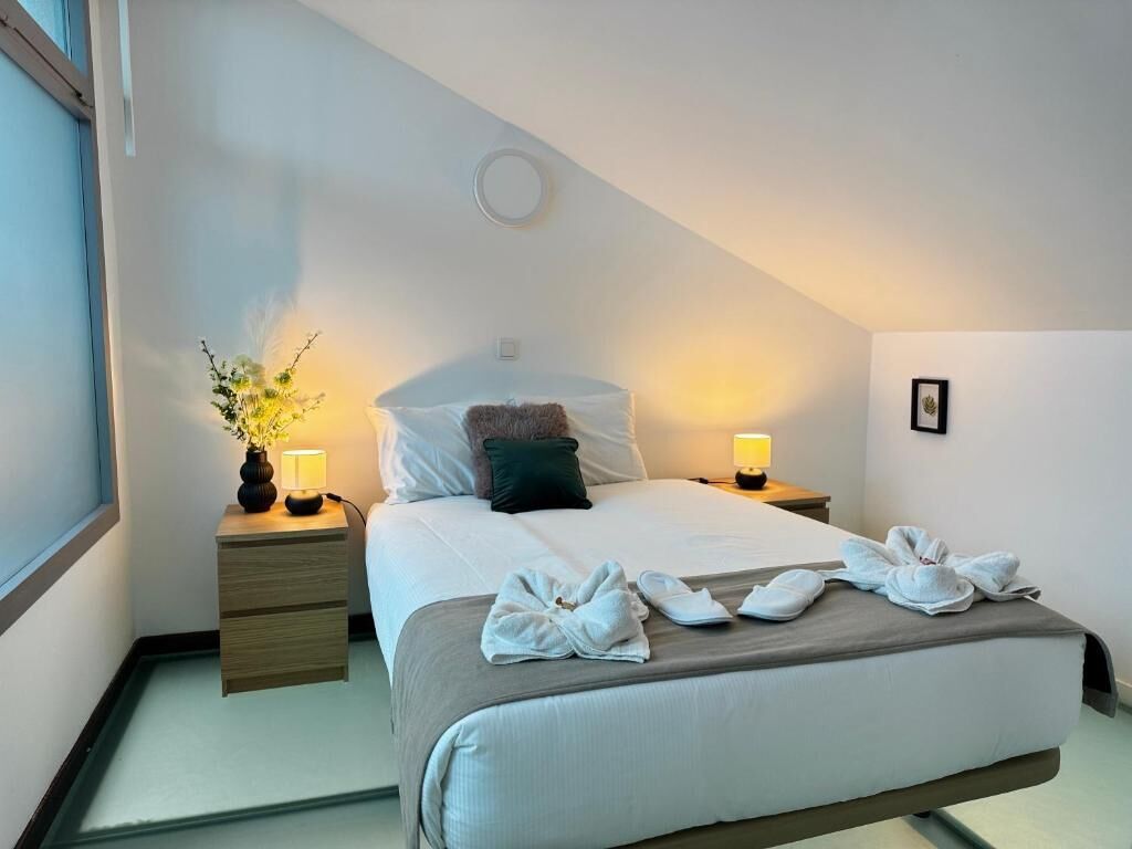 A hotel room with a bed, bedside tables, lamps, and towels.