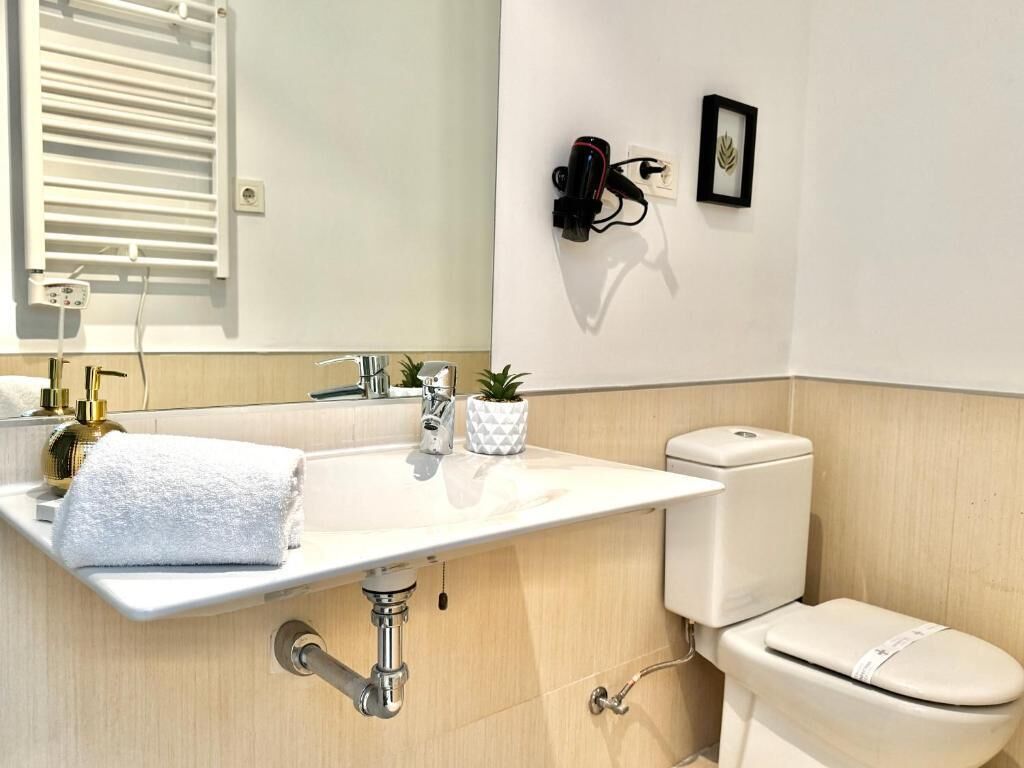 A modern bathroom with a white sink, a toilet, and a towel rack.
