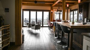 A spacious kitchen with a large island, wooden flooring, and a view to the outside. - Magique | Hot Tub & 360° St. Lawrence River View (Les Éboulements)