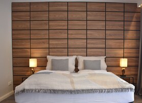 A neatly made bed with a patterned blanket and pillows, flanked by two bedside lamps on wooden nightstands.