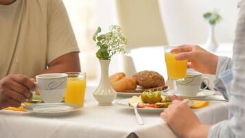 A breakfast setting with a table, a vase with flowers, and a plate of food.
