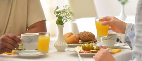 Una mesa con flores en un jarrón y un plato de comida para el desayuno.