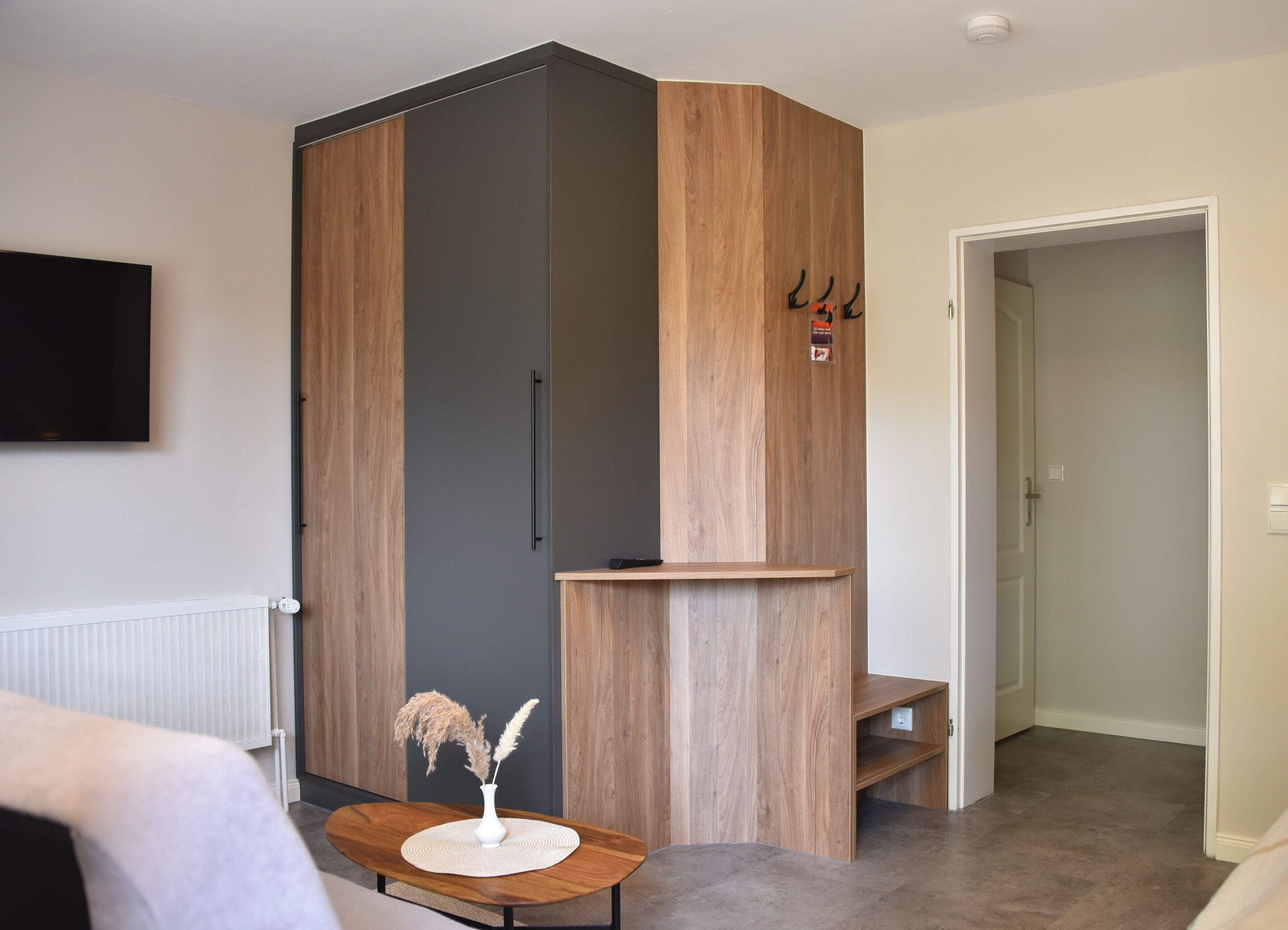 A modern room with a wardrobe, a small table with a vase, and a radiator.