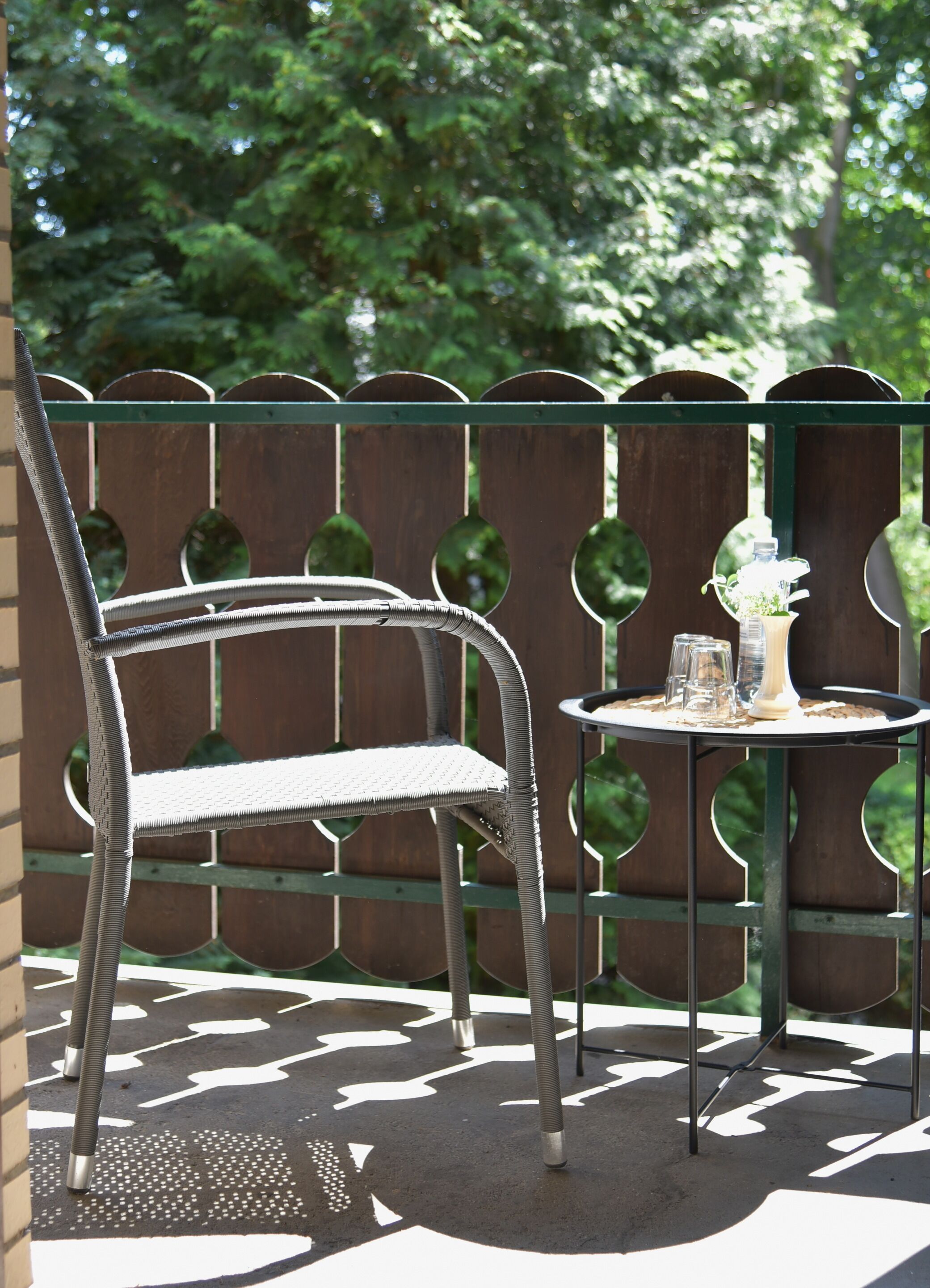 Juego de silla y mesa metálico en un patio con un cerco de madera al fondo.