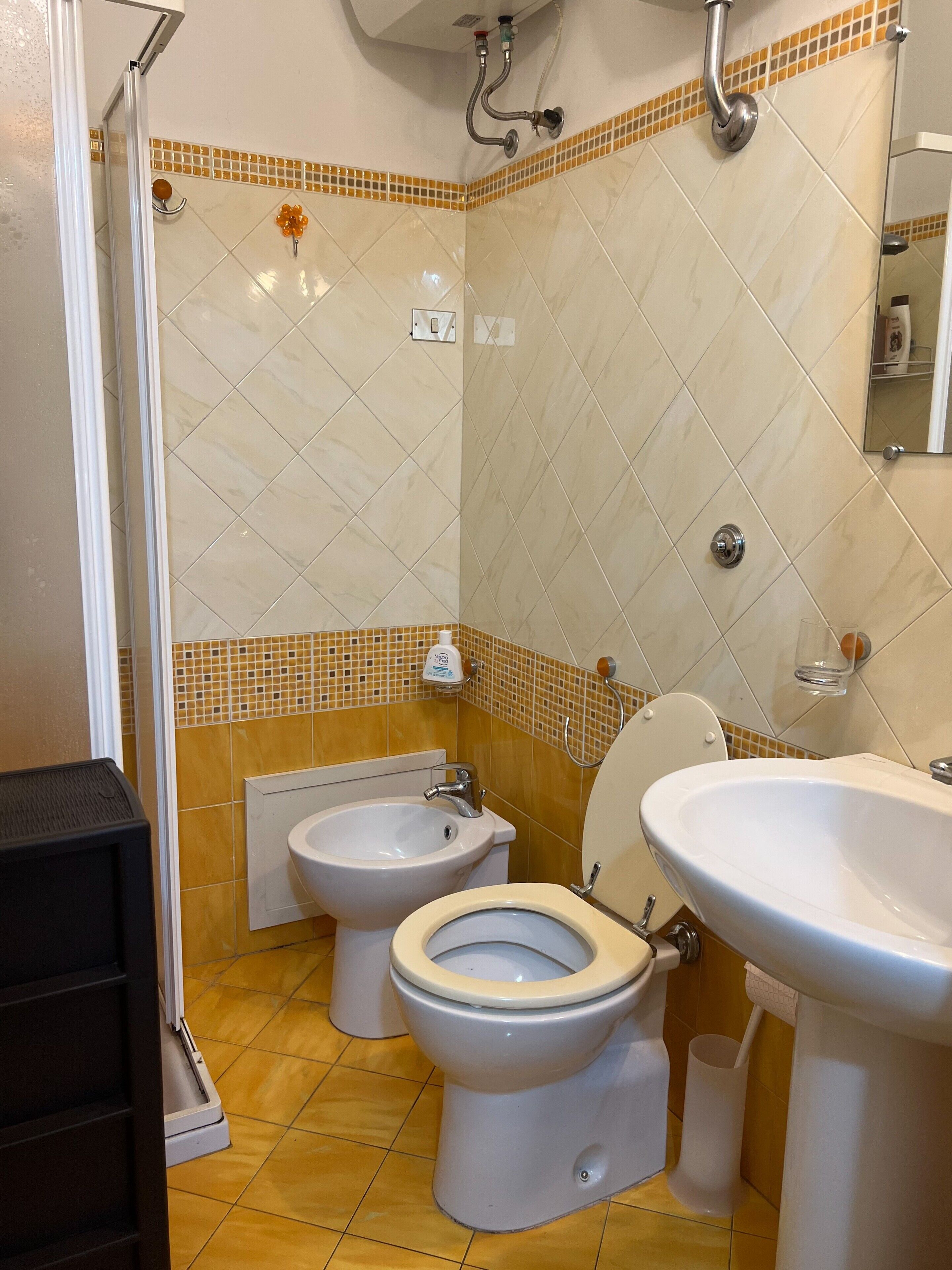 Un bagno con servizi igienici, bidet e lavabo, pareti piastrellate e zona doccia.