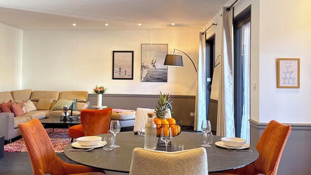 A modern living room with a round dining table, two orange chairs, and a sofa. - Appartements Hôtel & Spa Le Madeloc Collioure Centre (Collioure)