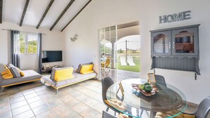 A modern living room with a glass dining table, a sofa set, and a TV. - CASA LYDIE - ÉVASION CRÉOLE AVEC PISCINE (Saint-François)