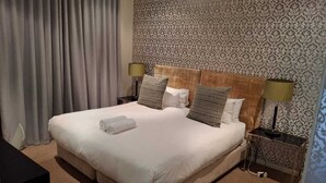 Ein Hotelzimmer mit einem großen Bett, strukturiertem Wandpapier und zwei Nachttischen mit Lampen.