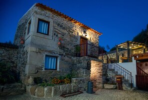 Un edificio de piedra con un balcón, una escalera y una puerta de madera.