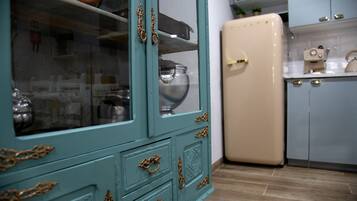 Una cocina con un mueble azul turquesa, un refrigerador color beige y una encimera blanca.