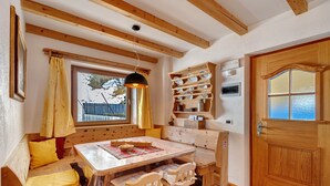 Un interior de madera con un área de asientos con bancos, una mesa y una puerta con ventanal.