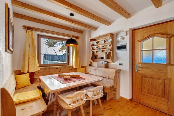 A wooden interior with a bench seating area, a table, and a door with a window.