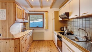 Una cocina con armarios de madera, una ventana con vistas al exterior, un horno empotrado y un lavamanos.