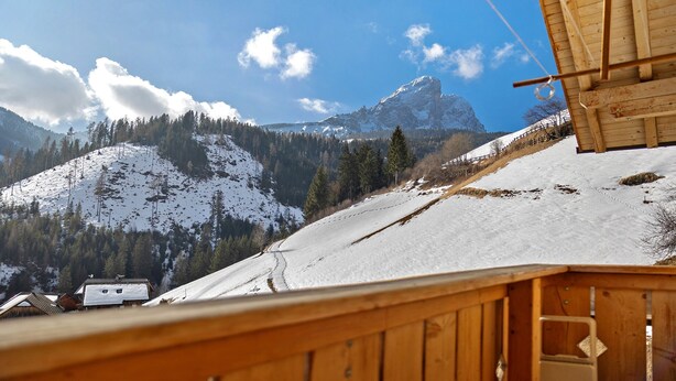 Una cabaña de madera con vistas a montañas nevadas y un cielo despejado.