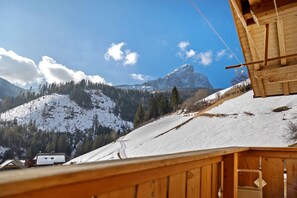 A wooden cabin with a view of snow-covered mountains and a clear sky.
